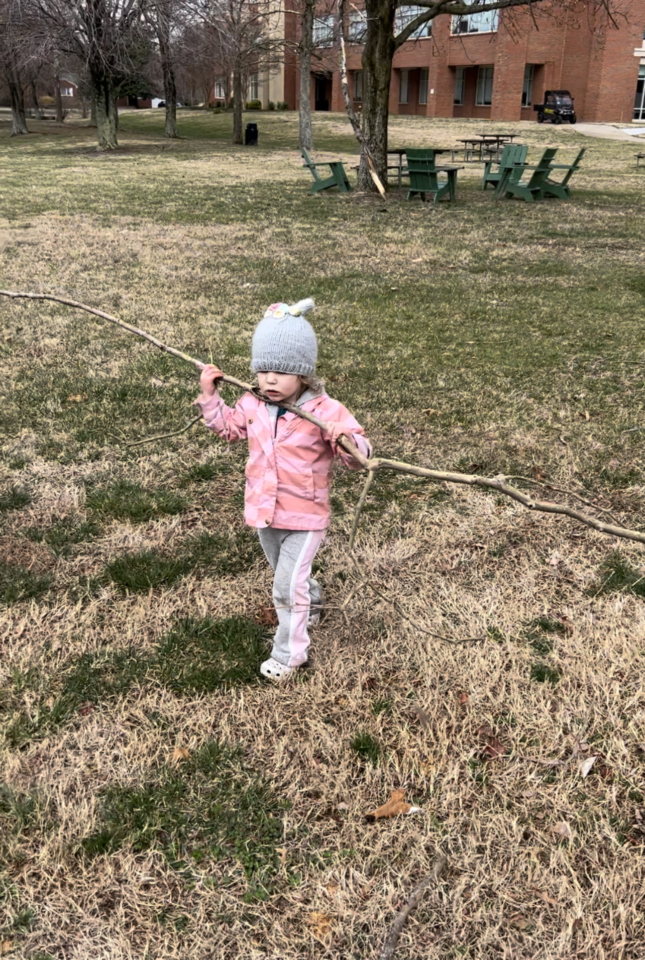 Toddler picking up sticks on the ground after a storm.