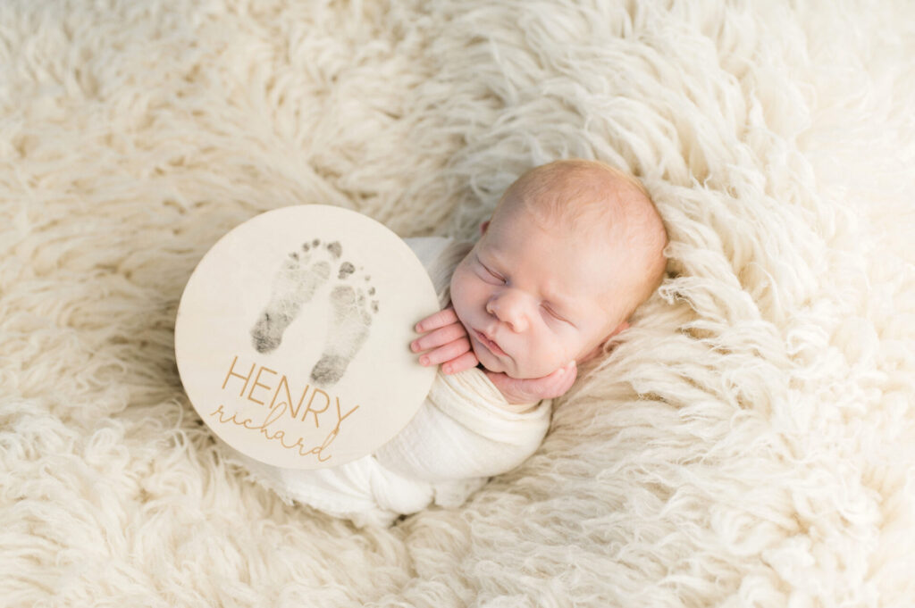 Newborn with wooden name sign