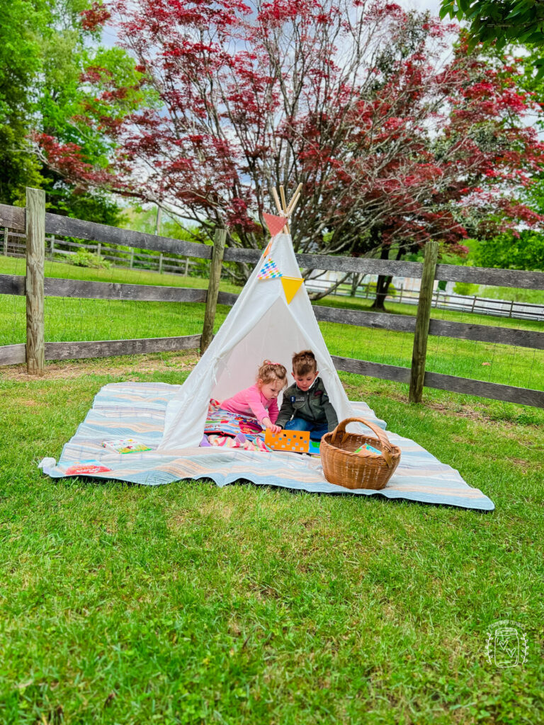 Building strong sibling relationships with a young boy and girl reading together in a tent.