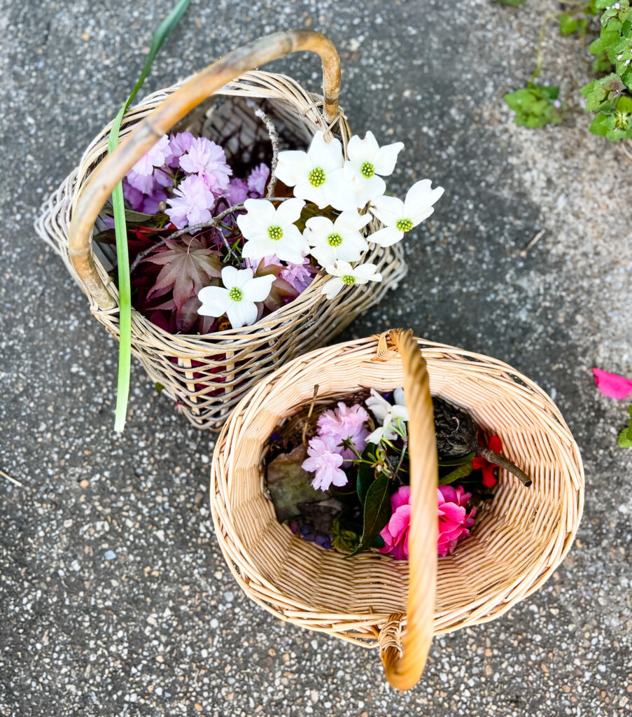 Two baskets full of nature items, such as flowers, sticks, leaves, and weeds.