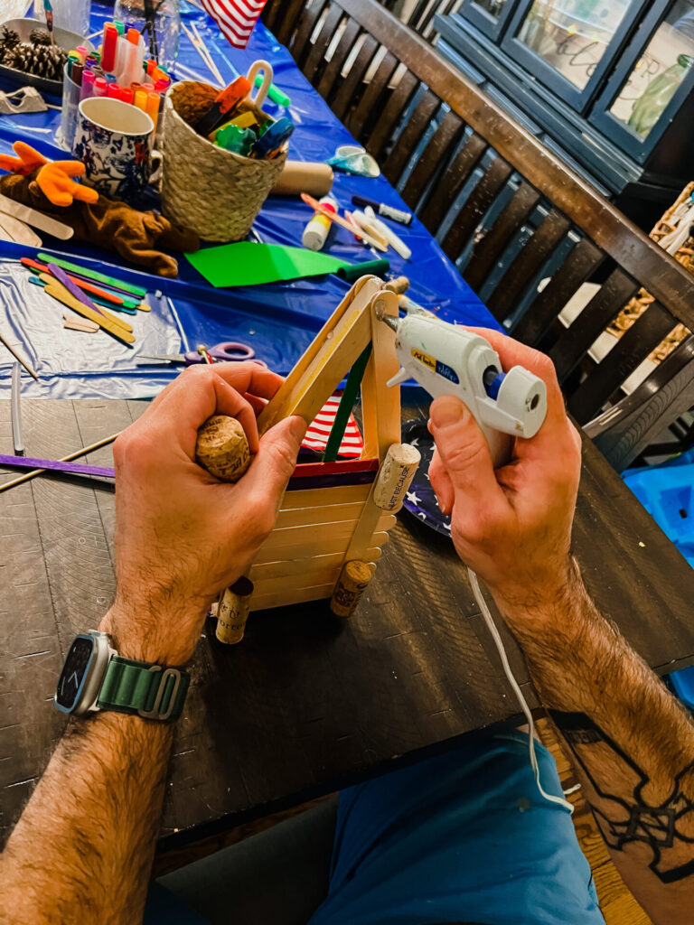 DIY Boats: Male hands using a hot clue gun with popsicle sticks