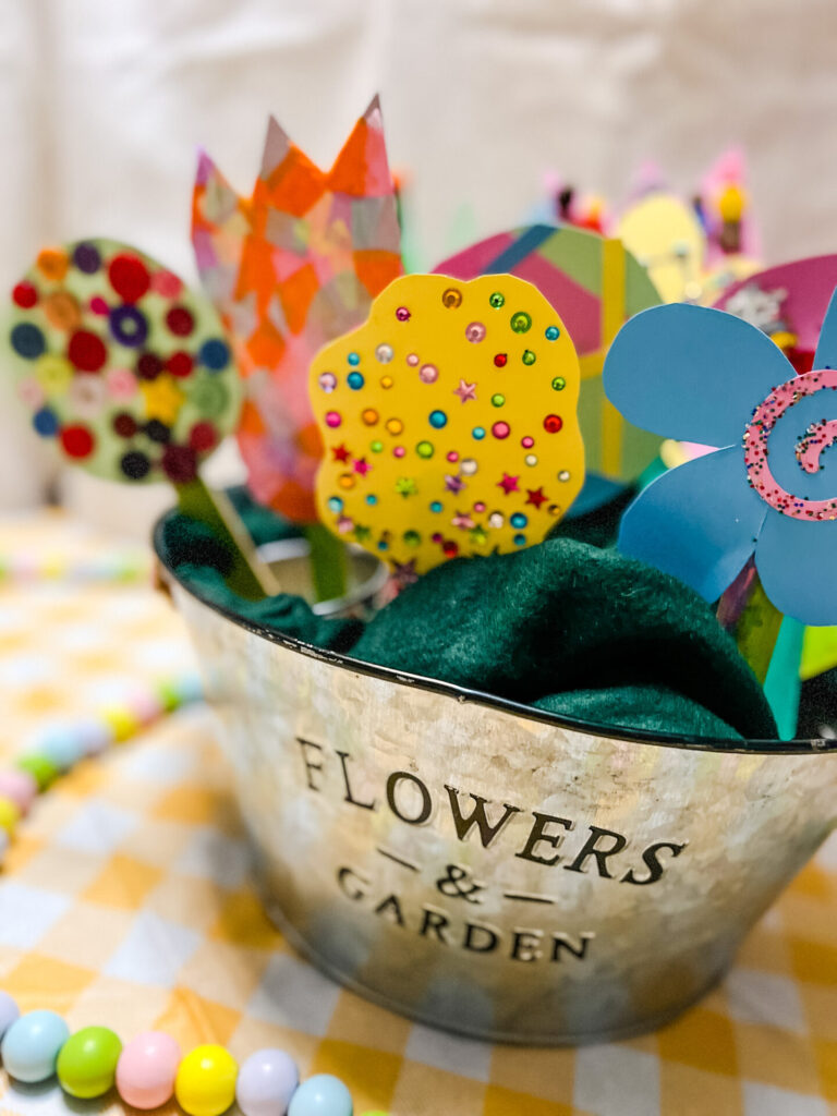 Spring Flowers made from cardstock paper, buttons, pom poms, confetti, popsicle sticks, and more craft items. 