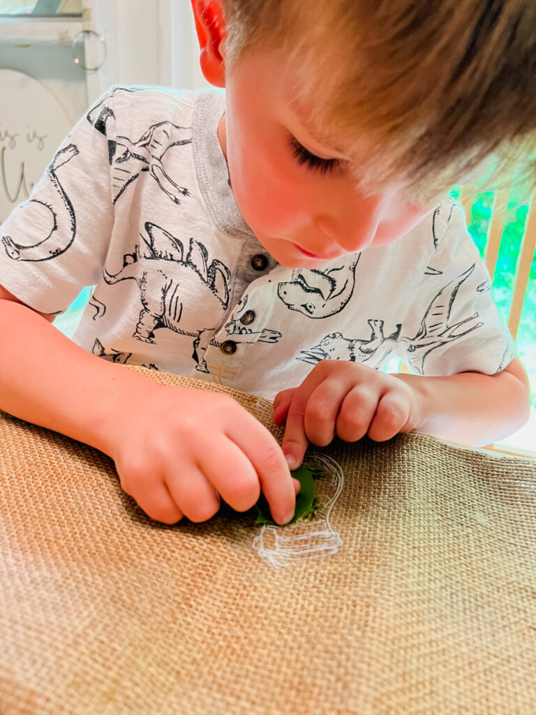 Young boy pressing flowers onto transparent stickers.