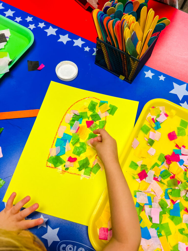 Summer Crafts - Child's hands working on tissue paper popsicle craft.