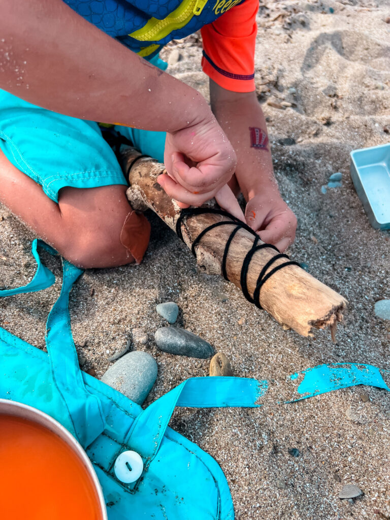 Beach Art with black string around a stick.