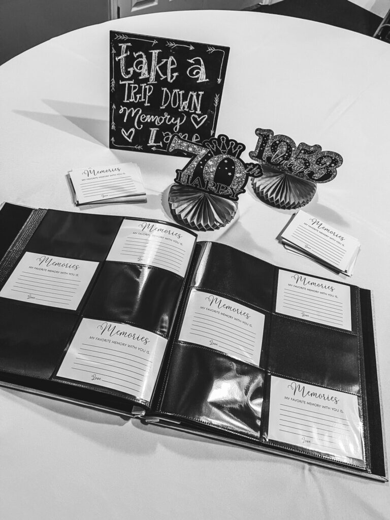 Memory Card Table Set Up with small chalk board that says, "Take a walk down memory lane" memory cards, photo album, and 70th birthday table decorations.