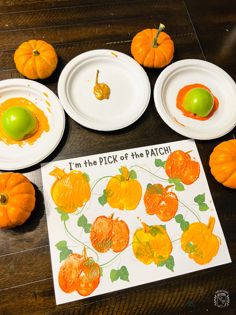 Pumpkin Apple Stamping Craft, Printable with pumpkin vines and oranges pumpkins made from apple stamps. Paper plates with orange paint and mini pumpkins are also displayed in the picture. 