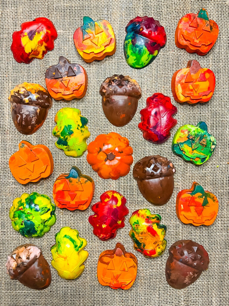 Fall Crayons consisting of pumpkins, leaves, and acorns are displayed on burlap material.