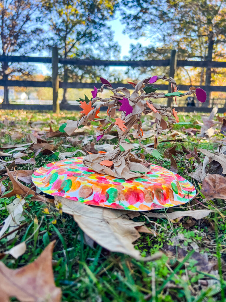 Fall Tree Craft displayed outside in front of a wooden fence.
